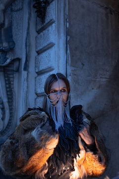 Confident woman in a chain veil holds a huge fur coat, dramatic gothic fashion portrait