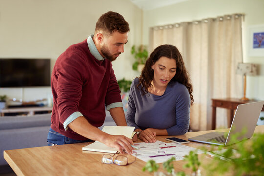 Pensive couple discussing home finance with bills