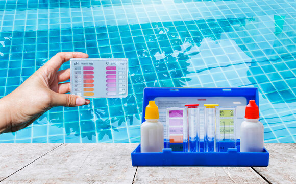 Water tester test kit in girl hand over blurred swimming pool water background, quality water testing test kit, pool maintenance and service business concept