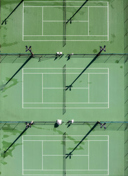 Aerial view of tennis courts with long shadows cast by floodlights on the green surfaces in Coimbra, Coimbra, Portugal.