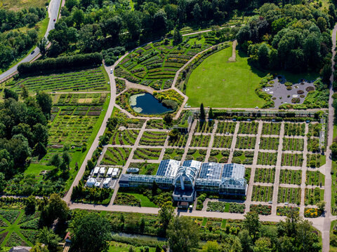 Aerial view of Vytautas Magnus University Botanical Garden with structured garden beds, a central glass greenhouse, and a small pond in Kaunas, Kauno apskritis, Lithuania.