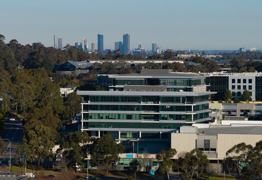Aerial view of a modern office building in Bella Vista with the Parramatta skyline in the distance, surrounded by trees and urban infrastructure in Bella Vista, New South Wales, Australia.