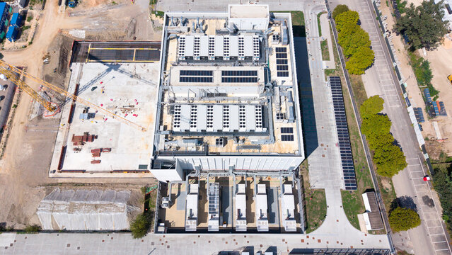 Aerial view of the Equinix ML5 data center featuring rooftop cooling units and solar panels, situated next to a construction site in Castelletto, Lombardia, Italy.
