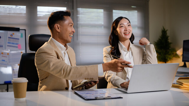 Asian business colleagues celebrating successful teamwork during an office meeting.