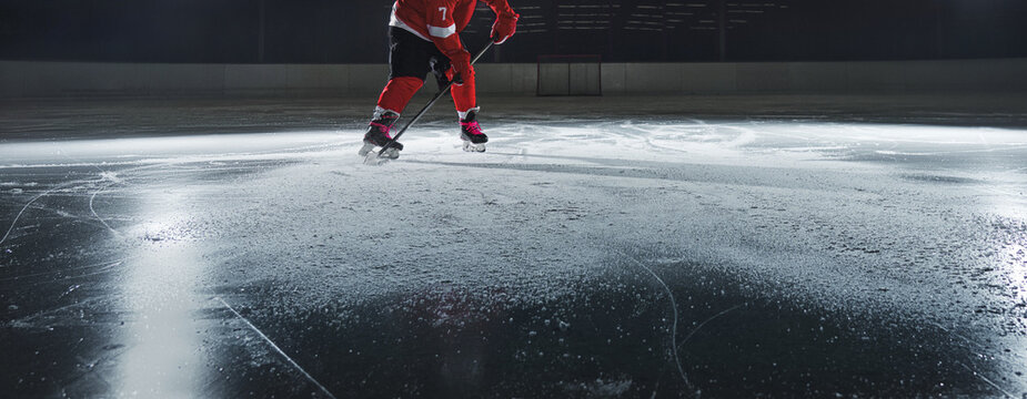 Ice hockey rink arena with professional player shooting the puck with hockey stick.