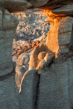 Beautiful vertical view of a natural stone arch framing unique badlands desert rock formations at sunset