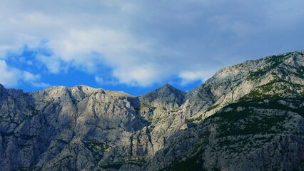 Obraz premium Big mountain peak scene with sun light and white clouds on a blue sky, mountain landscape background