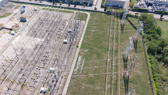 Aerial view of the Terna Baggio electrical substation with high-voltage power lines and metal transmission towers in an industrial area in Settimo Milanese, Lombardia, Italy.