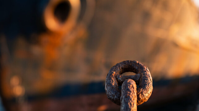 Close-up of a rusty anchor chain link in warm sunlight