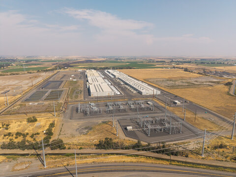 Aerial view of a large industrial data center facility with an electrical substation surrounded by dry fields in Hermiston, Oregon, United States.