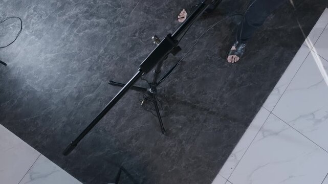 Unrecognizable male podcast host taking black headphones from microphone stand preparing for true crime audio broadcast interview in modern digital media studio top down high angle authentic shot