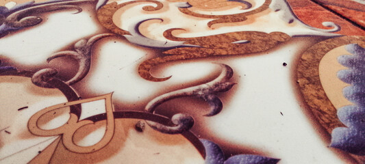 Ornate ceramic tile featuring intricate swirls and floral patterns in warm brown and soft purple tones © Arg Studio