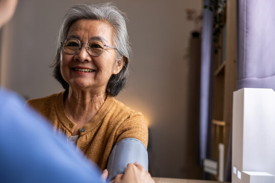 Elderly Asian woman smiling during home consultation with healthcare worker