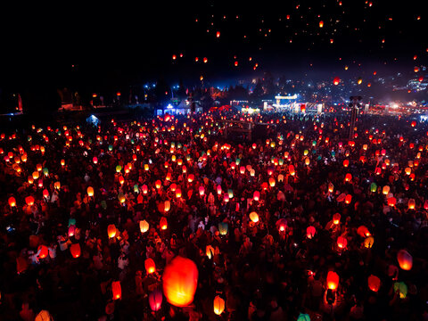 Aerial view of Dieng Culture Festival with hundreds of glowing sky lanterns floating above a large crowd at night in Indonesia.
