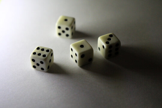 Four white dice with black dots cast black shadows on a white background