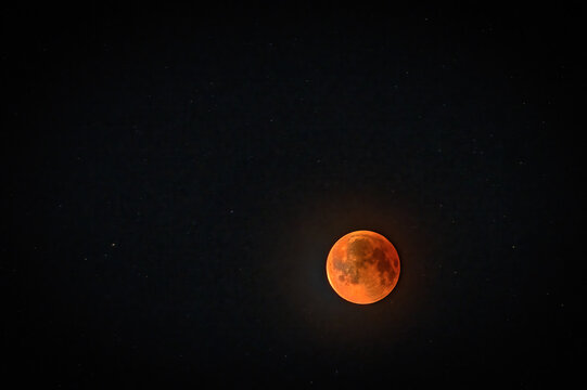 View of a lunar eclipse blood moon glowing in the dark night sky over Jahanian, Pakistan.