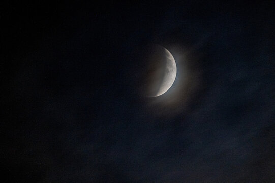 View of a partial lunar eclipse with a glowing crescent moon partially obscured by the earth's shadow against a dark night sky in Jahanian, Pakistan.