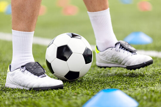 Close-Up of Coach Standing Over Soccer Ball on Turf Pitch with Marker Cones - Football Player Footwork and Skill Control Concept