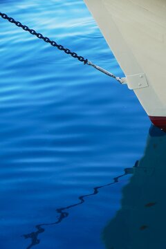 White wooden boat on the sea in harbor with reflection in water, sea transportation and nautical boat background
