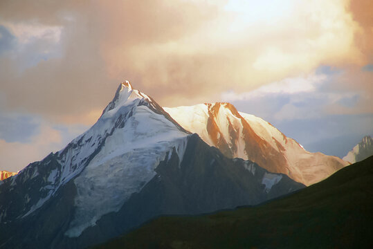 View of the snow-capped Boultar Peak illuminated by golden hour light with dramatic clouds in the background in Pakistan.