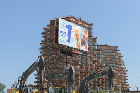 heavy machinery (Blackcore Environmental Inc), roadside billboard spectacular of a McDonald's Canada beverage advertisement, and the silhouette of Aqualuna Condos at Merchants' Wharf, East Bayfront, T