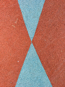 Colorful surface with red and blue shapes on a playground or sports area showing a geometric pattern during midday light