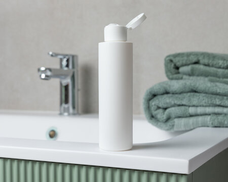 White flip top cosmetic bottle mockup near towel on green bathroom vanity. Cosmetic packaging