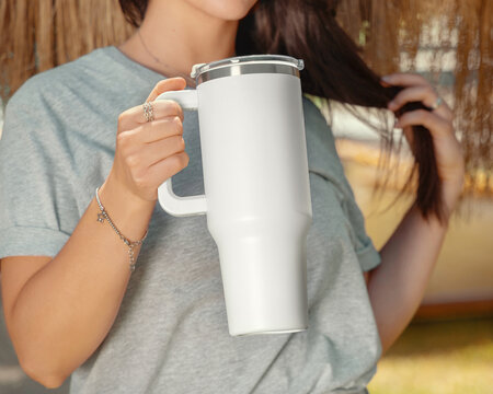 Blank white 40oz tumbler mockup, young woman outdoors, hand close up. Lifestyle scene