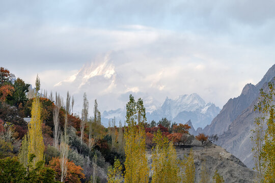 View of Mashabrum Peak rising above autumn-colored trees and mountain slopes in Hushe, Pakistan.