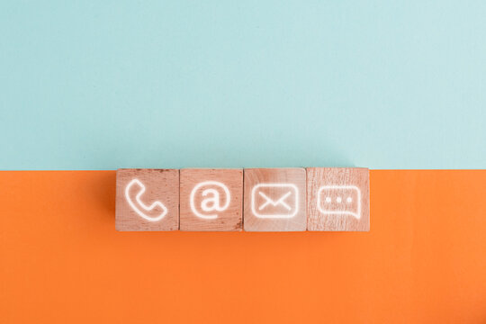 Wooden blocks on table showing phone, email, address and live chat icons. Contact us about customer service center connectivity concept. Internet communication via website