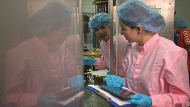 Quality control worker reviewing production data on clipboard during bottled beverage filling process in factory
