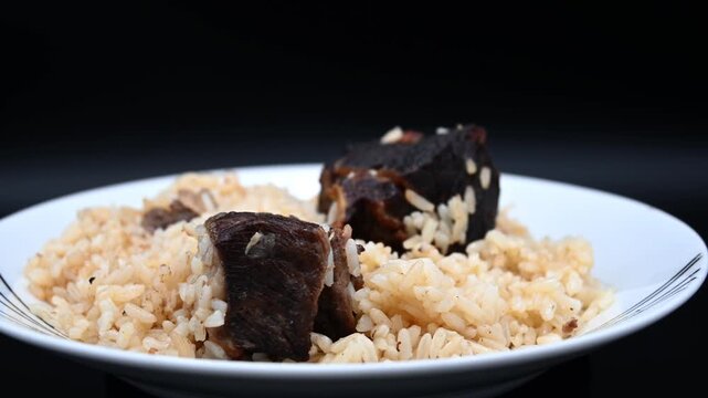 Tender Braised Beef Meat Chunks Served Over Savory Seasoned Rice Pilaf on a Plate Traditional Comfort Food Meal