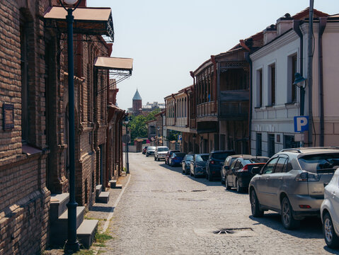View of a quiet cobblestone street lined with historic brick buildings and traditional wooden balconies in the city of Telavi, Kakheti, Georgia.