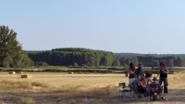 Happy group of young people relaxing on folding chairs. Friends spending time together, talking and enjoying a sunny day in the countryside