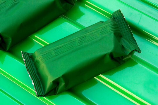 Two blank green snack bar wrappers on a matching green ribbed surface