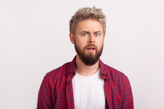 Shocked bearded man with eyes wide open raised eyebrows reacting with sudden disbelief amazement posing isolated over white background