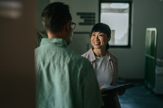 Asian woman smiling while discussing with male colleague