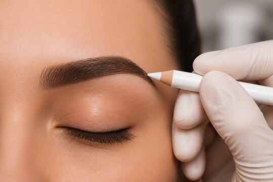Professional technician marking eyebrow arch for permanent makeup