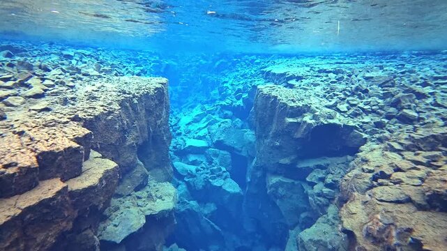 アイスランドの透明度の高い淡水の裂け目を進む水中映像、溶岩岩の割れ目とターコイズブルーの水（Iceland Underwater Fissure in Crystal Clear Freshwater 4K）