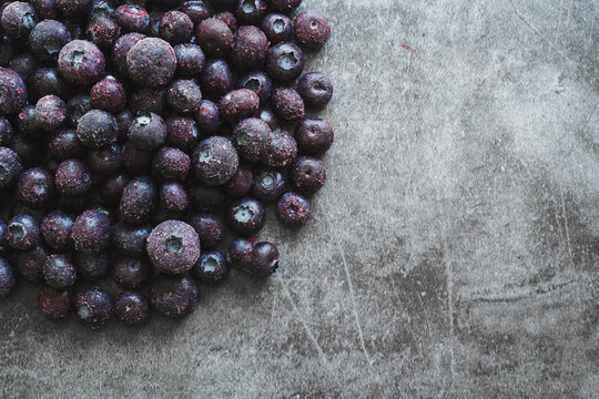 Heap of frozen blueberries on gray background with copy space.