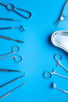 Set of stainless surgical instruments and tools - scalpels, scissors and others - on blue table, top view