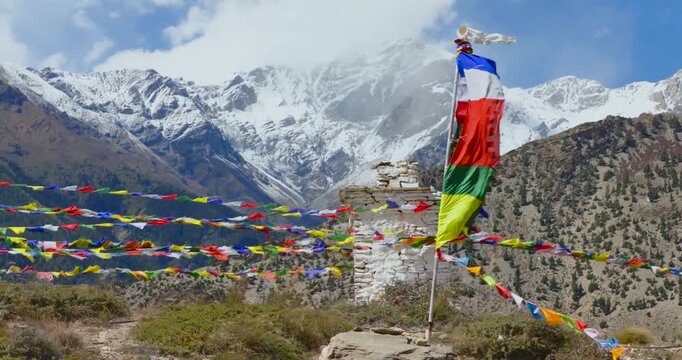 Buddhist prayer flags fluttering in wind against snowy himalayan mountain peaks.