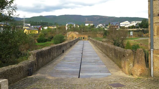 Road-level view crossing Ponte da Cigarrosa above the Sil River, with stone parapets leading toward the Valdeorras landscape between Pet&iacute;n and A R&uacute;a in Galicia, northwestern Spain