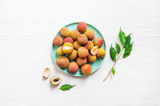 Exotic lychee fruit with green leaves on plate, top view. Healthy vegetarian meal