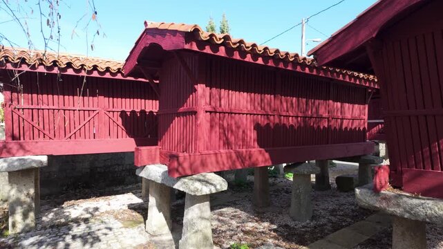 Close view of traditional red h&oacute;rreos in A Forxa, raised wooden granaries on granite supports used for crop storage in the rural municipality of Porqueira, Ourense, Galicia, Spain