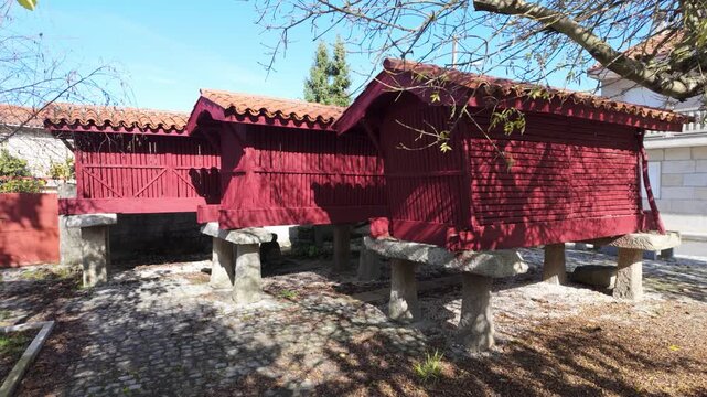 Close view of traditional Galician h&oacute;rreos in A Forxa, showing raised wooden granaries on stone supports beside village houses in the rural landscape of Porqueira, Ourense, Spain
