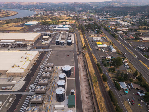 Aerial view of The Dalles data center featuring large industrial buildings, cooling towers, and storage tanks near a highway in The Dalles, Oregon, United States.