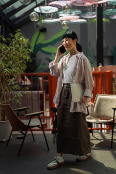 Asian woman communicating on smartphone in modern workspace