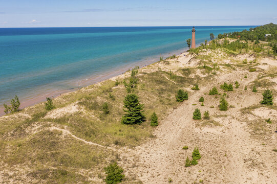 Aerial view of Little Sable Point Lighthouse surrounded by sand dunes, green trees, and the blue waters of Lake Michigan in Mears, Michigan, United States.