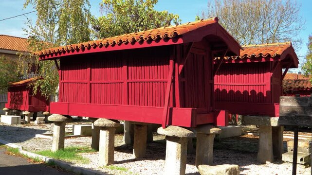 Traditional red horreo granary stands on stone pillars in A Forxa, Porqueira, Galicia, Spain